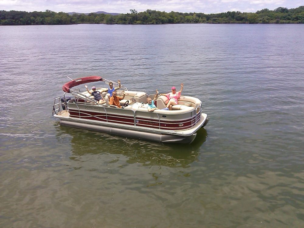 Guests waving from a red and tan pontoon boat on Lake LBJ
